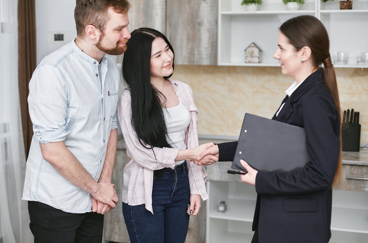 Mastering the First Impression: Your intriguing post title goes here A young couple shakes hands with a real estate agent during a home tour or negotiation in a modern setting.