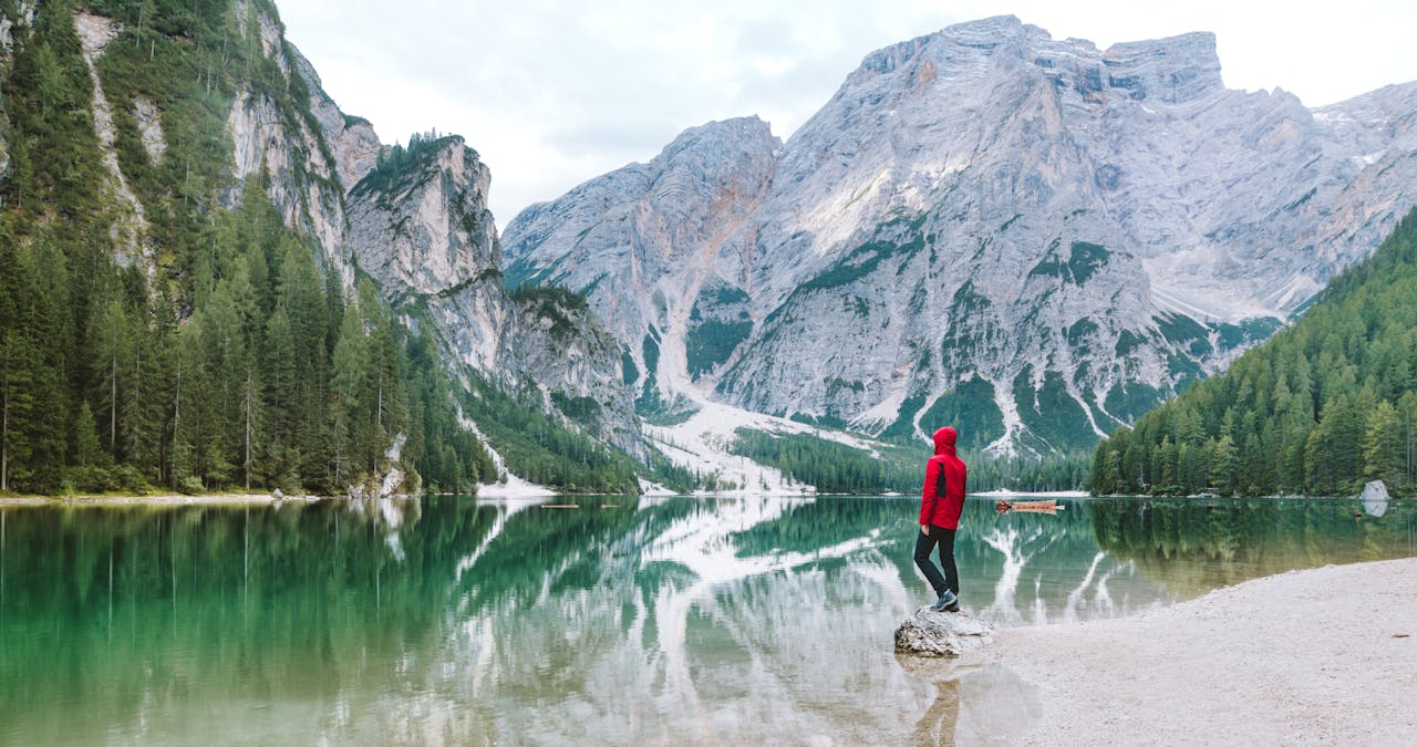 services-04 Person standing by the scenic Lake Braies with majestic Dolomite mountains reflected in the water.